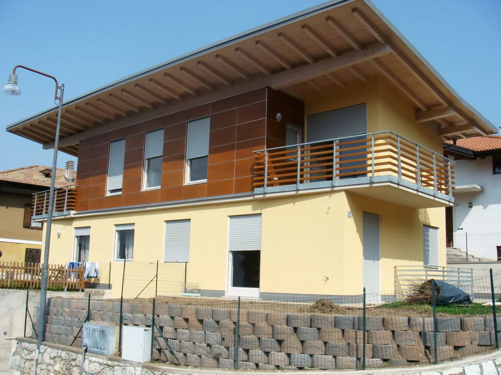 Abitazione bifamiliare alla Grotta di Villazzano, intonaco giallo e rivestimento in legno