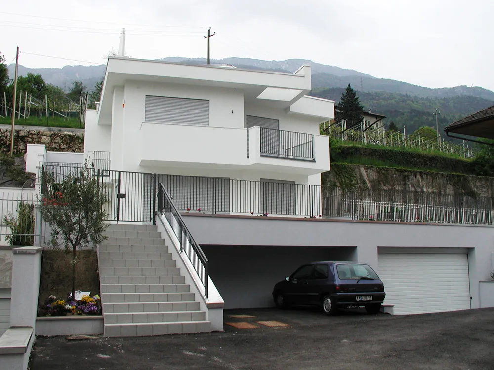 Costruzione monofamiliare a Villazzano, casa bianca con scala esterna e garage