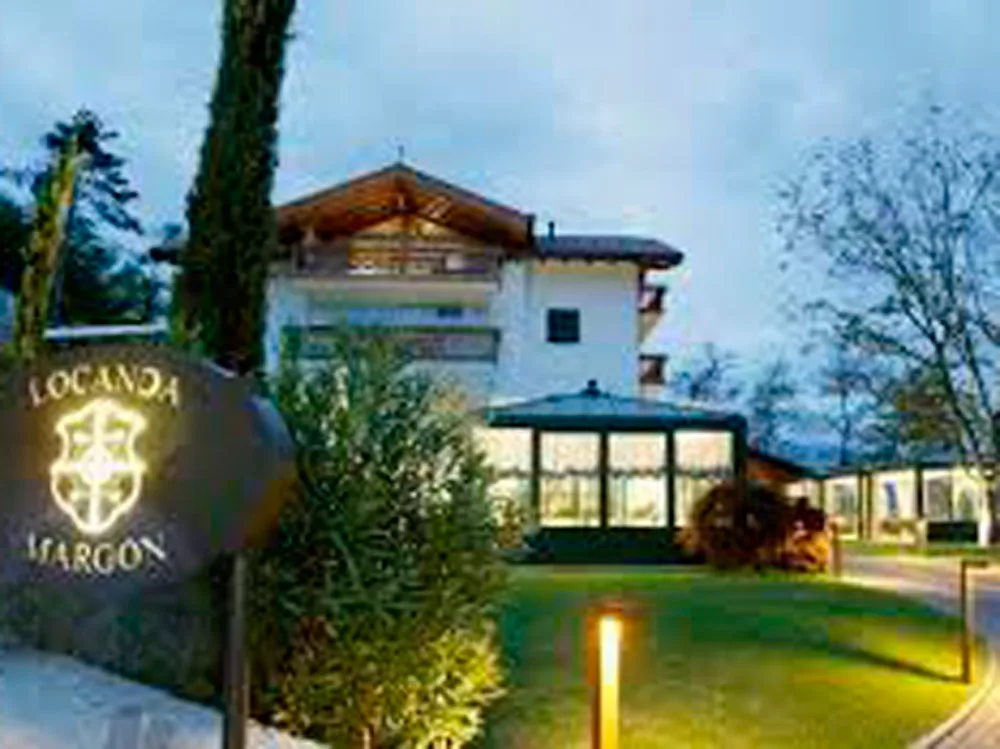 Villa Margon a Ravina, edificio con tetto in legno e giardino illuminato la sera